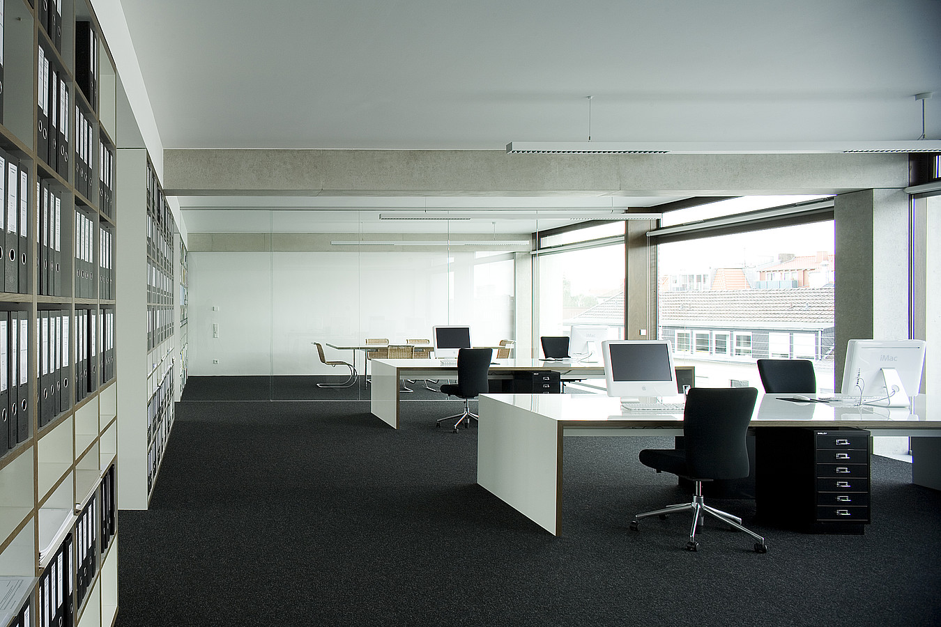 Bürohaus Hafenweg 24 Münster Das Bild zeigt eine Innenaufnahme des Büros Peter Bastian Architekten. Das Bild zeigt einen Teil des Großraumbüros. Auf der linken Seite befinden sich Einbauschränke. Im Hintergrund befindet sich der mit einer Glaswand abgetrennte Besprechungsraum.